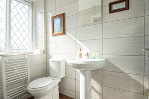 Un baño con inodoro, lavamanos y un cuadro en la pared.
