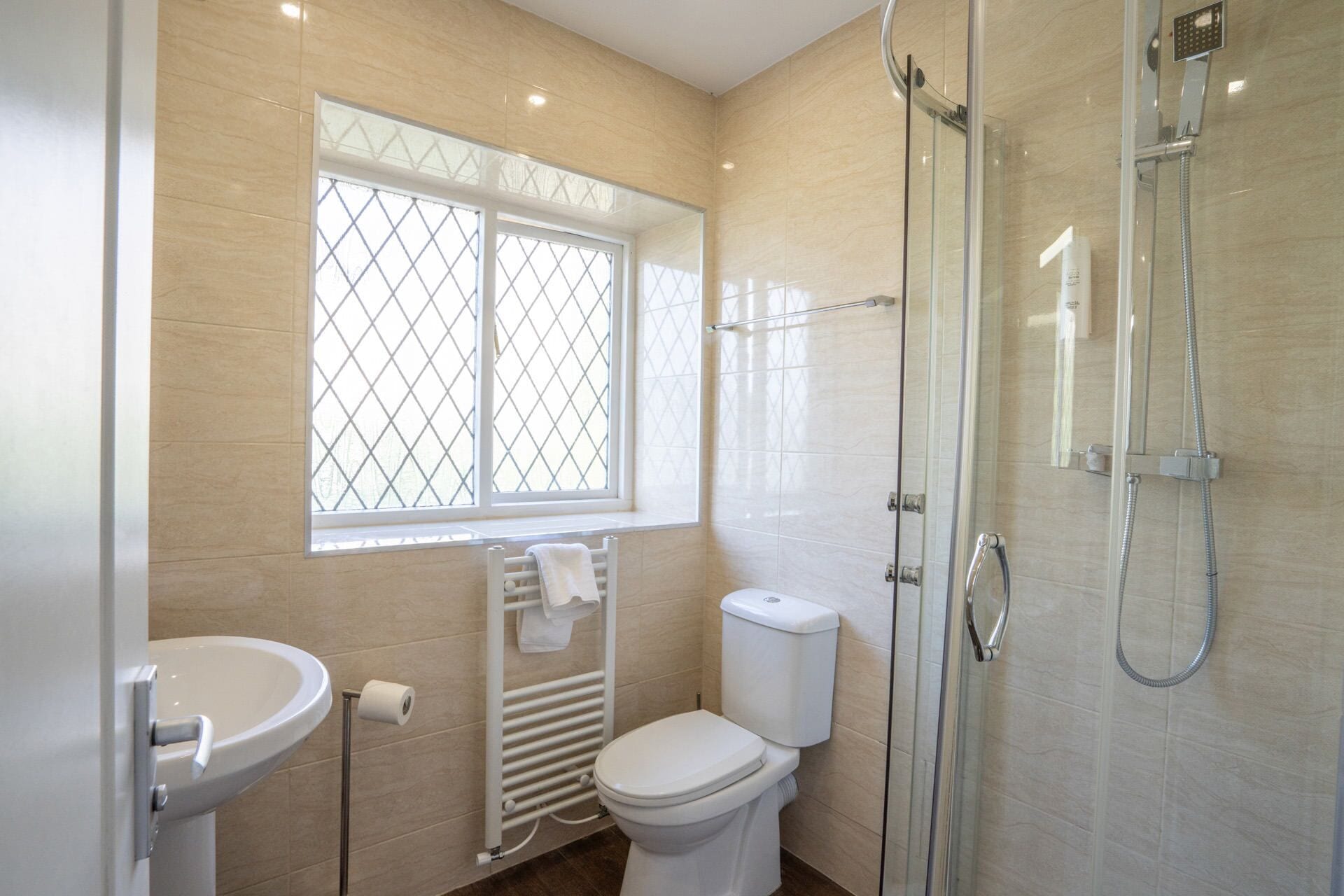 A bathroom with a toilet, sink, and glass shower enclosure.