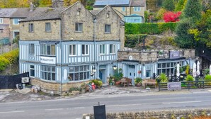 Un bâtiment traditionnel en pierre, doté d’une façade bleue, abrite un pub appelé « The Millstone », et une enseigne indique également « The Millstone ».