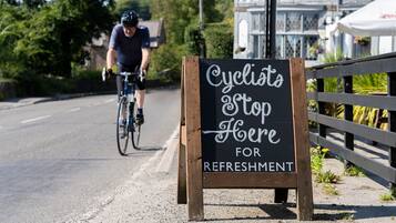 A signboard with 'Cyclists Stop Here for Refreshment' on a roadside.