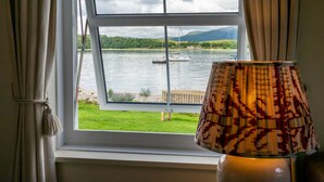 Ein Fenster mit Blick auf einen See, ein Boot und eine Wiese.