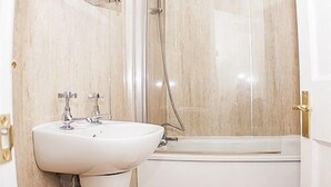 A bathroom with a white sink, a bathtub, and a shower enclosure.