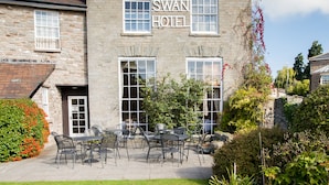 Ein Hotel namens 'SWAN HOTEL' mit einer Terrasse, die Sitzgelegenheiten im Freien und einem gepflegten Rasen bietet.
