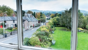 Blick aus einem Fenster auf eine Straße mit Häusern, einer Wegstrecke und Grünflächen.