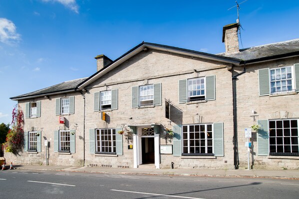 A two-story stone building with a central entrance, multiple windows with shutters, and a chimney. - The Swan at Hay Hotel (Hereford)
