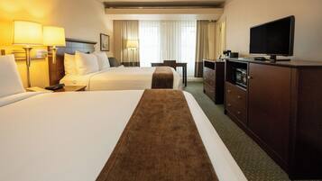 A hotel room with two beds, a TV, a desk, and a dresser.