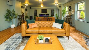 A living room with a leather sofa, a coffee table, and a TV in the background. - The Inn at Virginia Mason (Seattle)