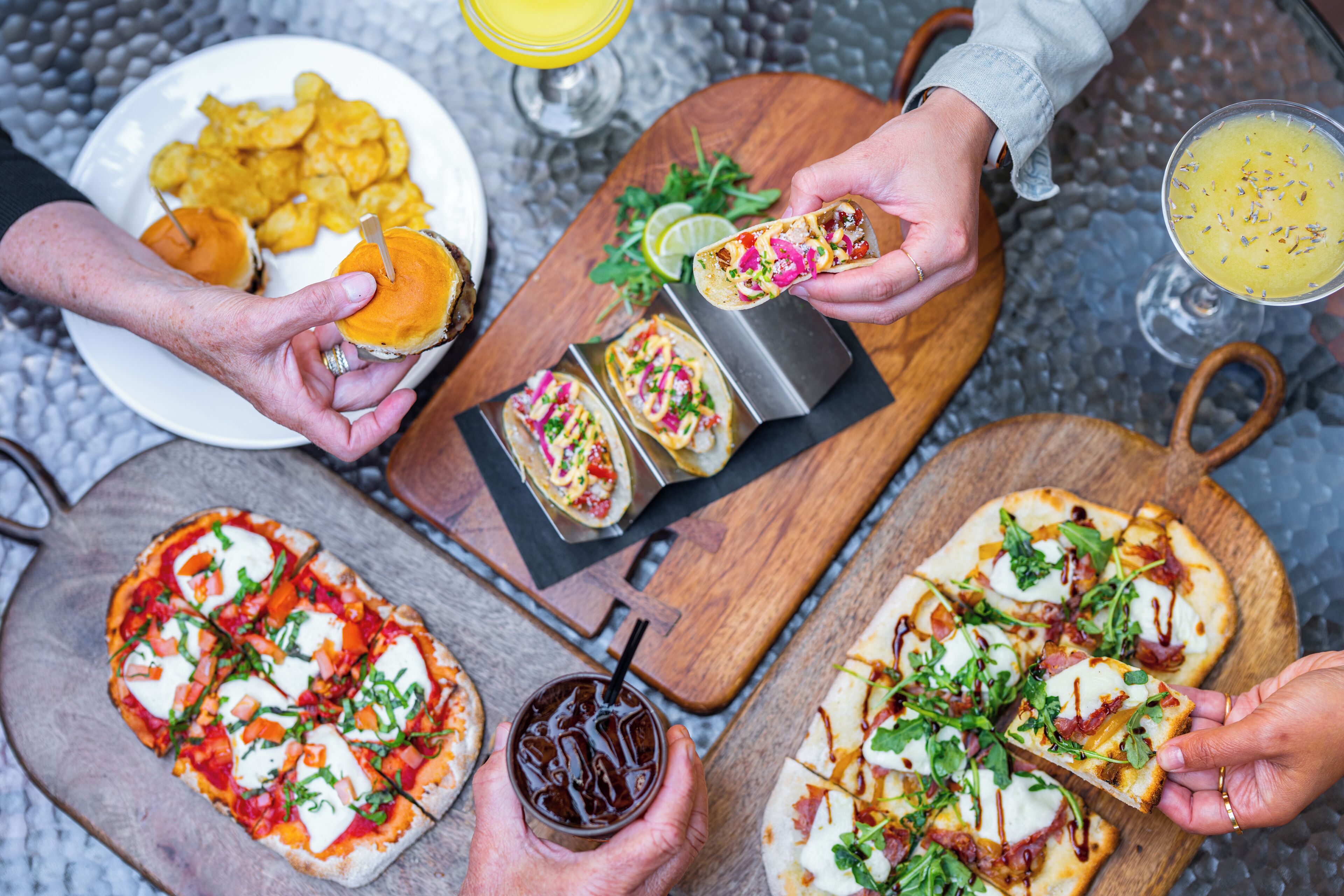A dining table with various food items including pizzas, tacos, and chips.