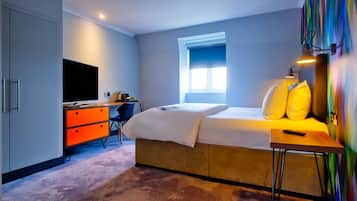 Una habitación de hotel moderna con cama, escritorio y televisor.