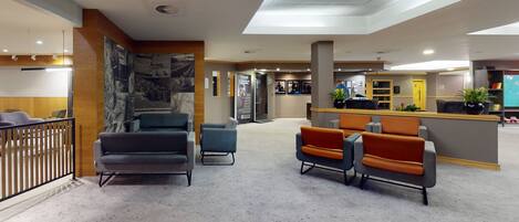 Una hall con zone salotto, una reception e un muro con fotografie.
