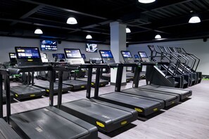 A gym with treadmills, exercise bikes, and digital screens displaying workout programs. - Village Hotel Hull (Hull)