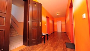 Un pasillo con puertas de madera y paredes anaranjadas, que da a una escalera.