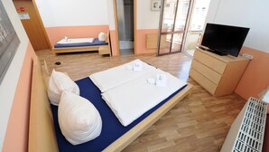 Una habitación de hotel con cama, televisión, un escritorio pequeño y la puerta del baño.