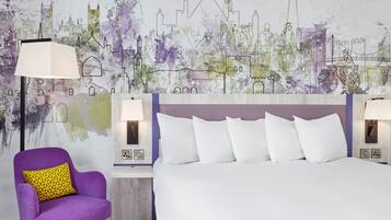 Una habitación de hotel con una cama grande, un sillón morado y un mural con vistas a la ciudad.