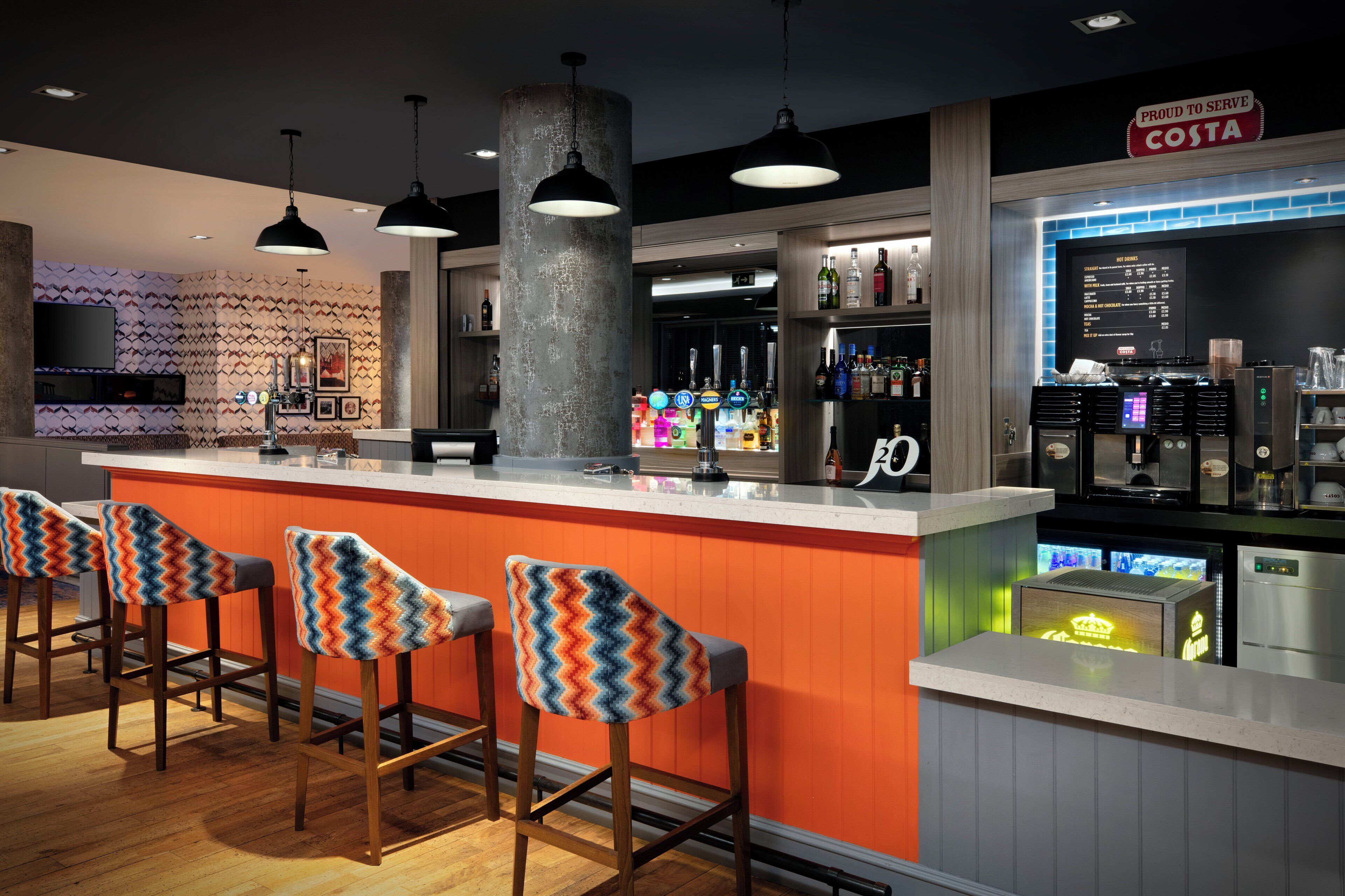 A bar area with a counter, stools, and a sign that says "Proud to Serve Costa."
