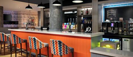 Een bar met een toonbank, krukken en een bord waarop staat 'Proud to Serve Costa'.