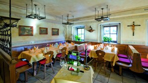 A restaurant with wooden benches and tables, a wine rack, and a crucifix on the wall. - Hotel Reitlwirt (Brixen im Thale)