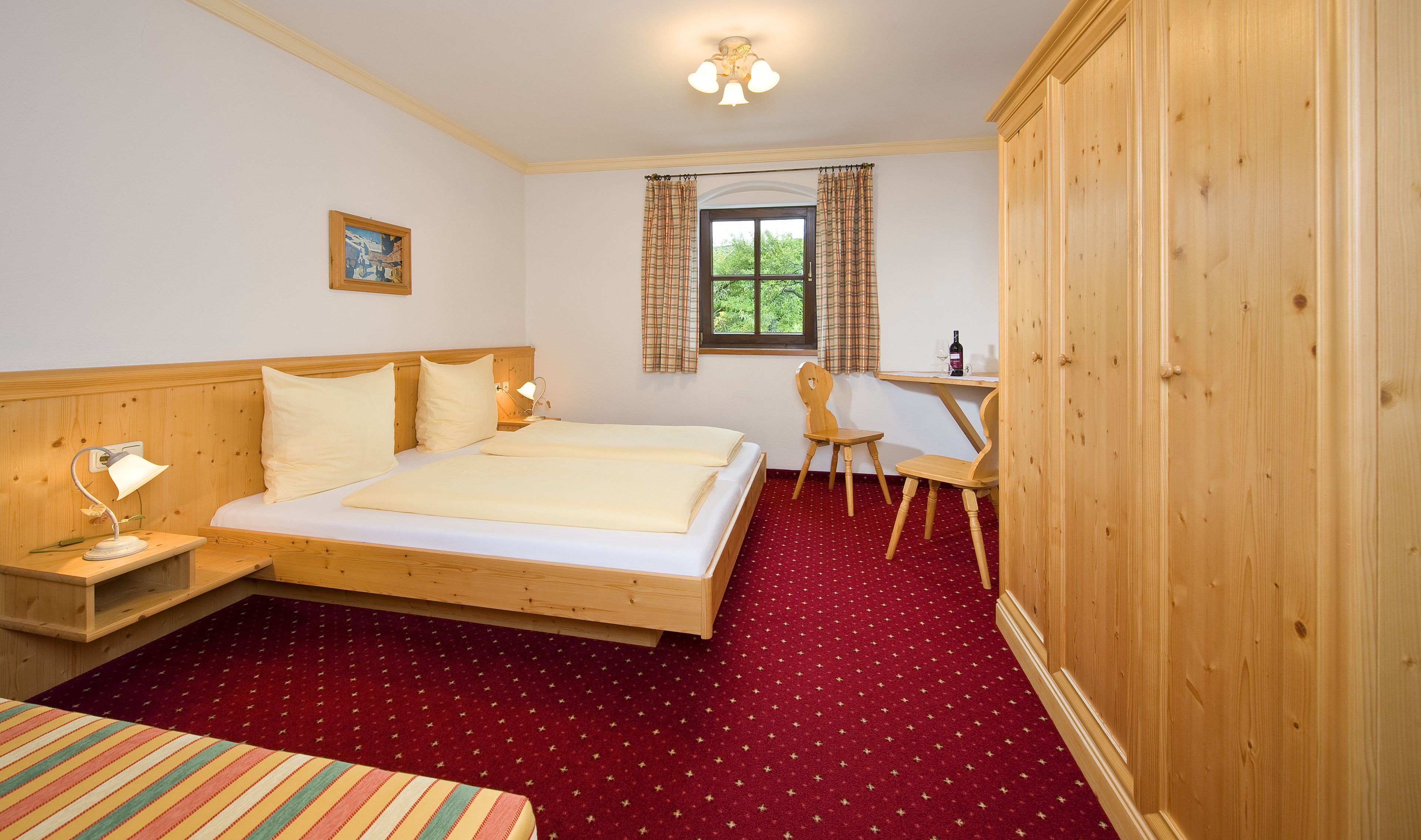 A bedroom with a wooden bed, a desk, and a wardrobe.