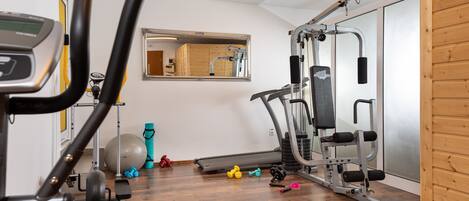 Un gimnasio en casa con equipo de ejercicio, un espejo y suelo de madera.