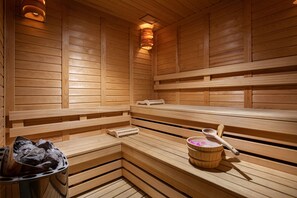 Una sauna de madera con bancos, un balde y una cuchara.