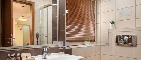 A modern bathroom with a large sink, mirror, and window with blinds.
