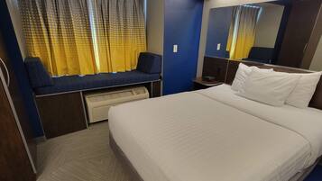 Une chambre d’hôtel comprenant un lit, un coin salon avec un bureau, un radiateur et un grand miroir.