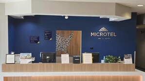 Tauleller de recepció amb una paret blava, panell de fusta i el logotip de Microtel Inn & Suites.