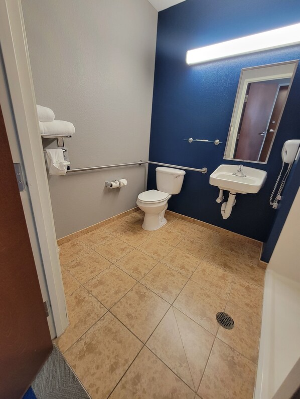 A bathroom with a toilet, sink, and mirror. - Microtel Inn & Suites by Wyndham Council Bluffs/Omaha (Council Bluffs)