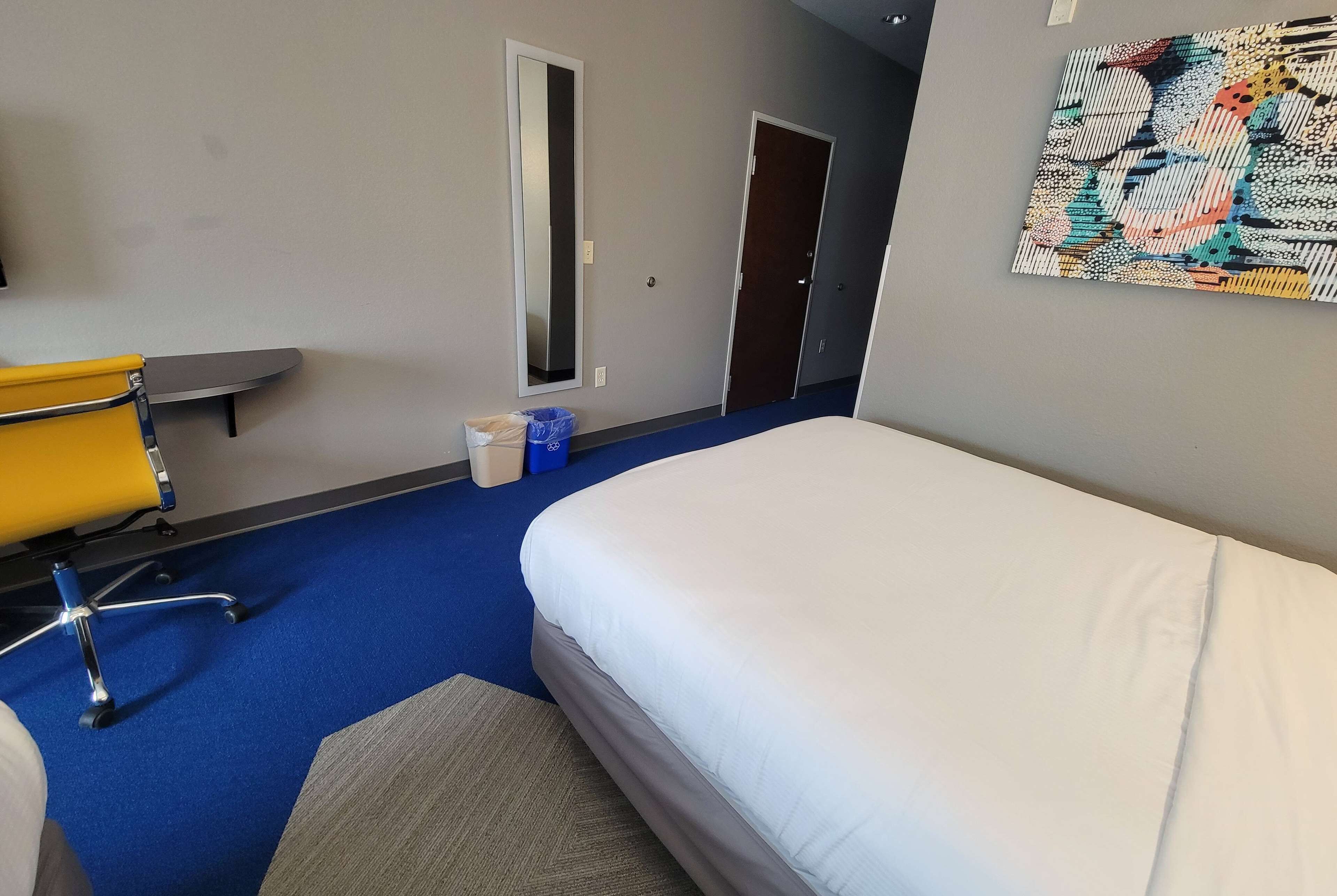 Ein Hotelzimmer mit Bett, Stuhl, Schreibtisch und einem Bild an der Wand.