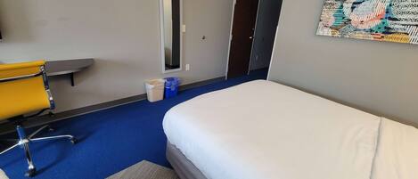 Ein Hotelzimmer mit Bett, Stuhl, Schreibtisch und einem Bild an der Wand.