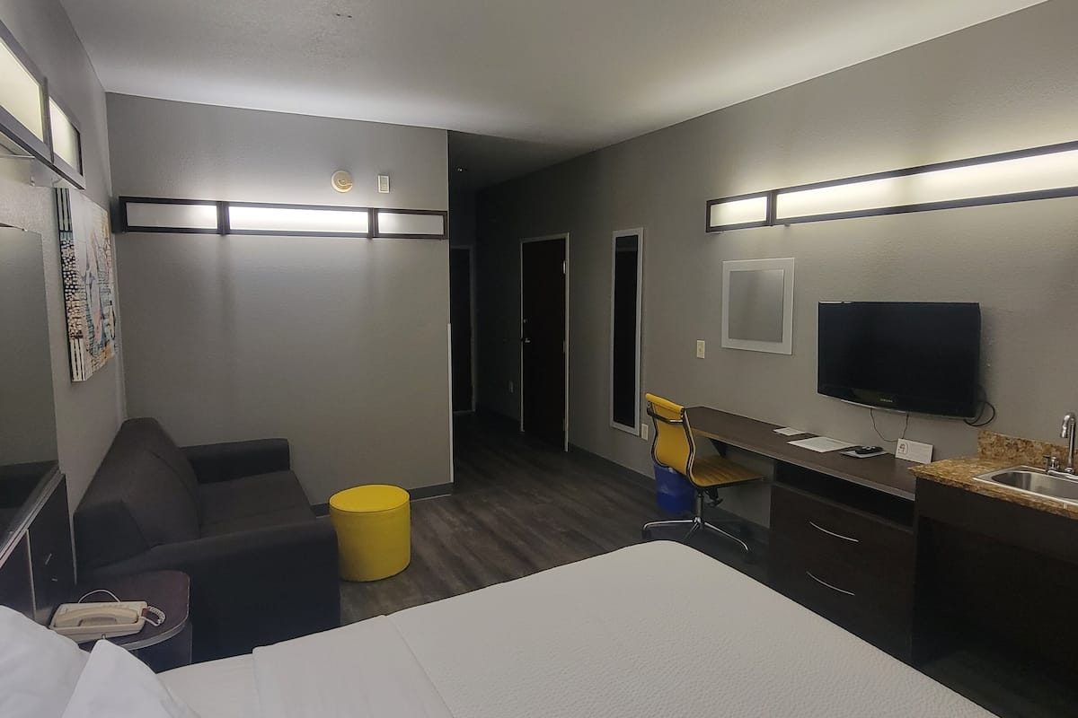 A hotel room with a bed, a desk, a chair, a television, and a small table with a telephone.