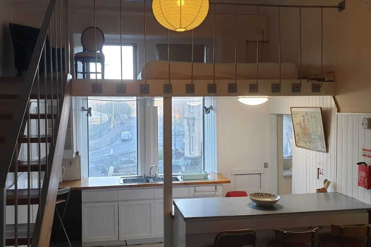 A kitchen with a window, a sink, and a dining area with chairs.