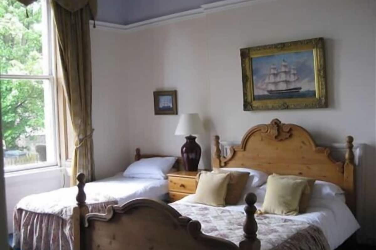 A bedroom with two wooden beds, a nightstand, a lamp, and a framed picture on the wall.