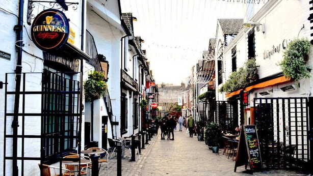 A narrow cobblestone street lined with traditional buildings, including a pub with a Guinness sign. - The Georgian House Hotel (Glasgow)