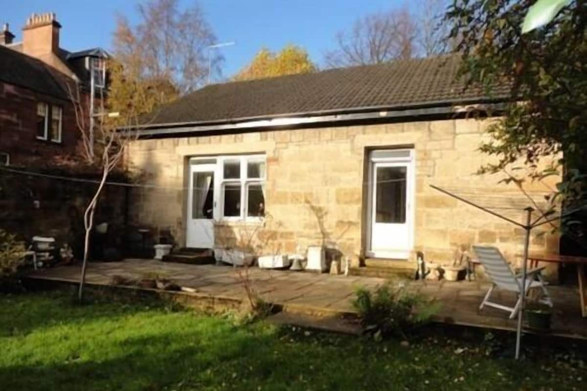 A stone house with a tiled roof and a small garden area.
