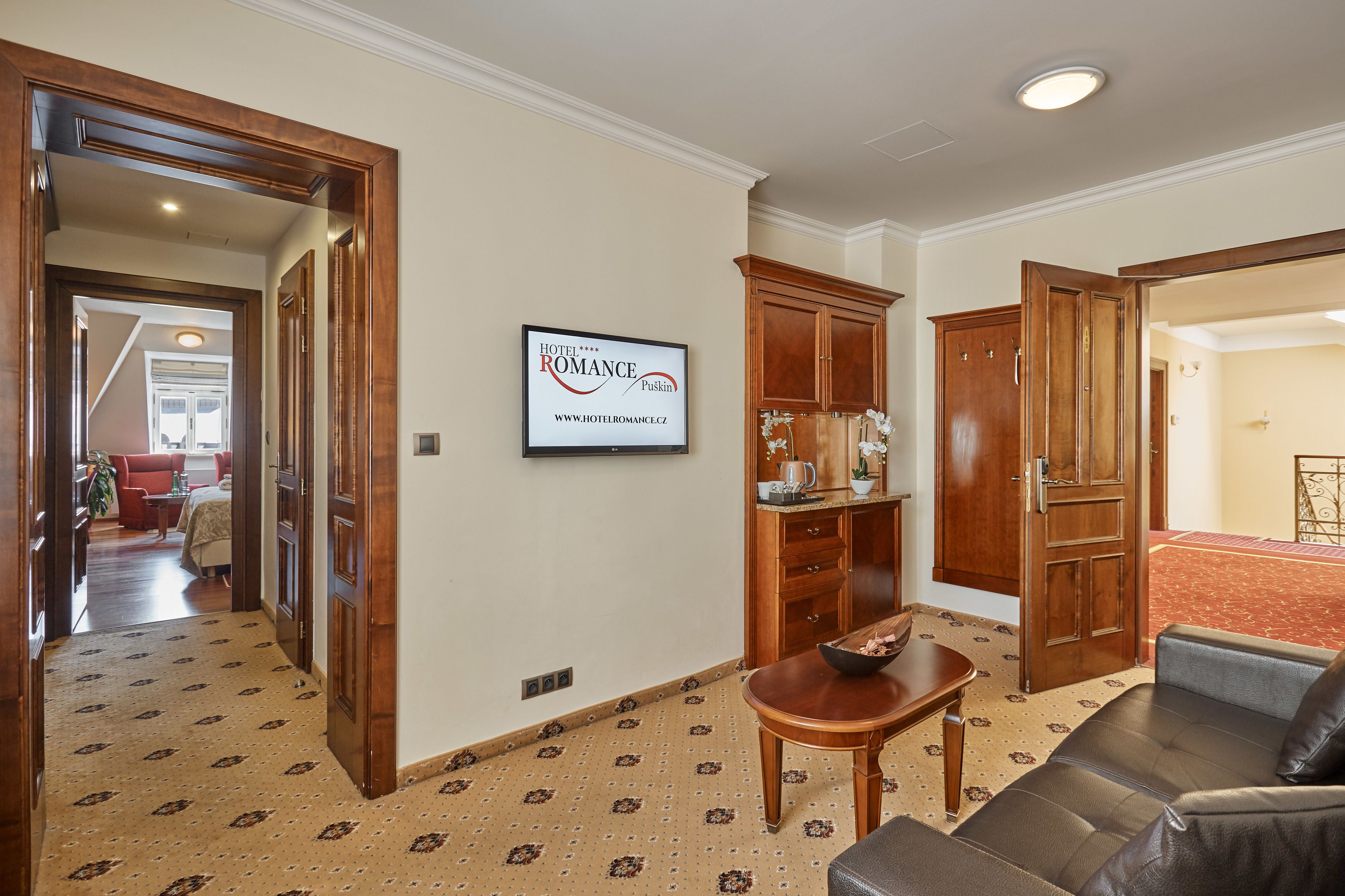 A hotel lobby with a sofa, wooden cabinets, a sign, and patterned carpet.
