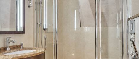 A modern bathroom with a glass-enclosed shower, a vanity with a granite countertop, and a large mirror.
