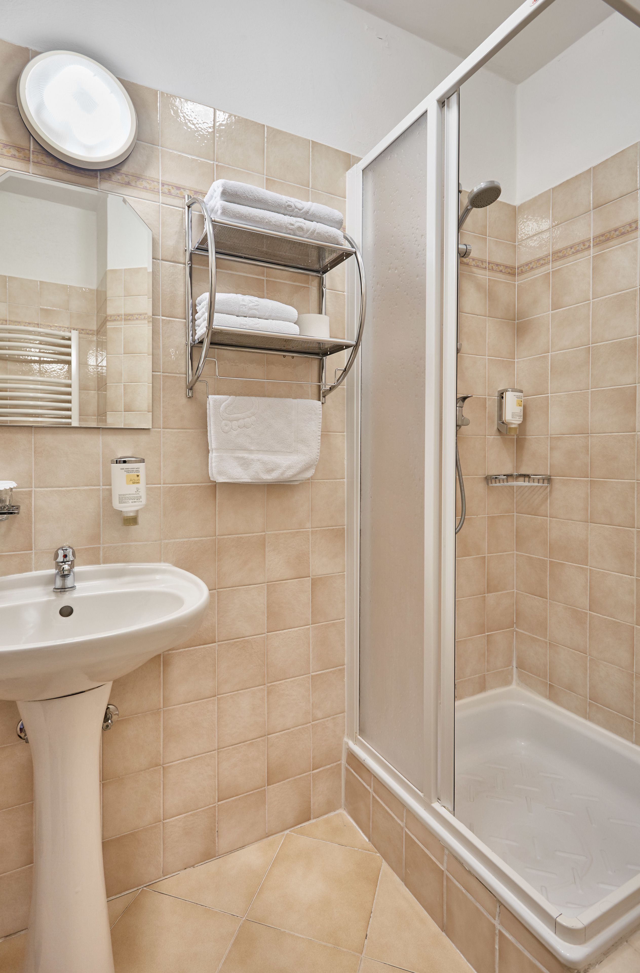 Ein Badezimmer mit Waschbecken, Spiegel, Handtuchhalter und Dusche.