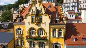 A yellow building with ornate architecture, multiple windows, and a balcony with flowers.