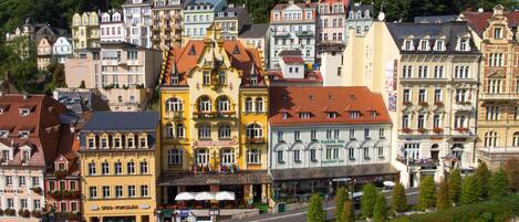 A historic town with colorful buildings, including a hotel with a red roof and a restaurant with outdoor seating.