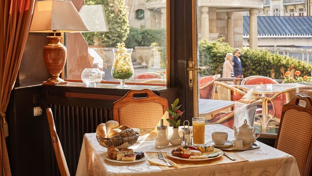 A dining table set with various dishes, a lamp, and a view of a cityscape through a window.