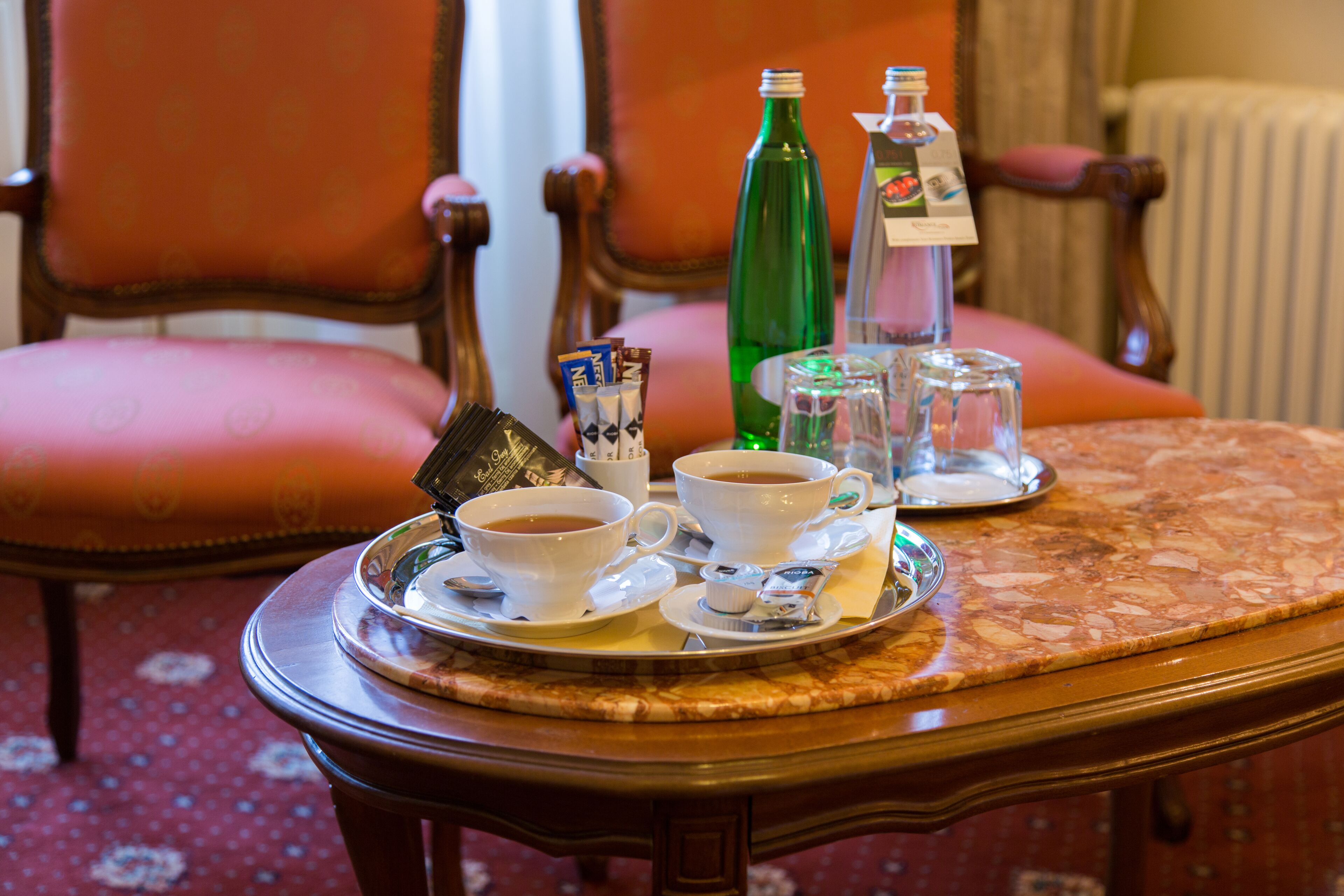 Un vassoio con due tazze di caffè, una bottiglia verde e un thermos su un tavolo.