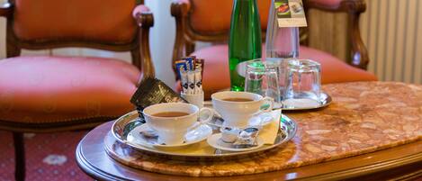 Un vassoio con due tazze di caffè, una bottiglia verde e un thermos su un tavolo.