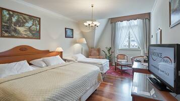 A hotel room with a bed, a desk, a television, and a window with curtains.