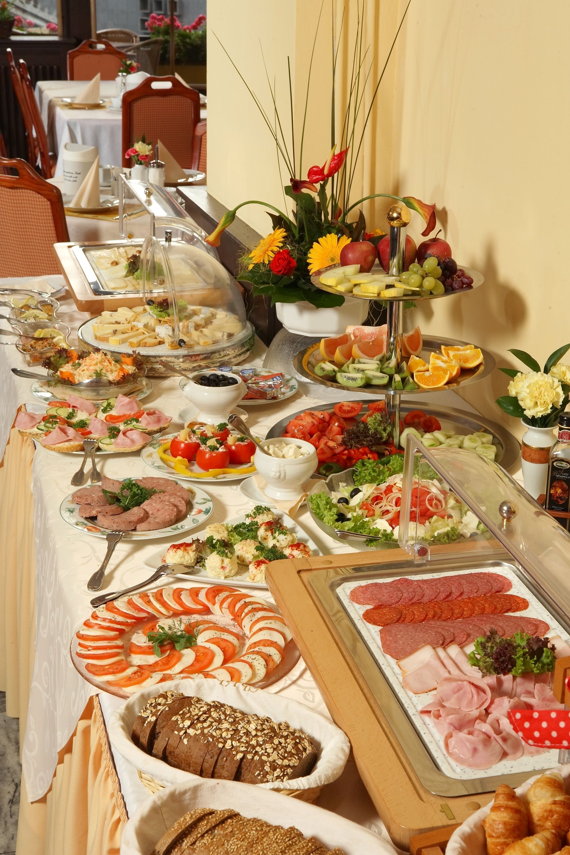 A buffet with various food items including fruits, vegetables, meats, and breads.
