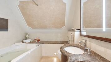 A modern bathroom with a bathtub, two sinks, a large mirror, and a vanity with a marble countertop.
