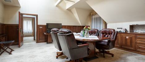 Un comedor espacioso con techo alto y tragaluces, que cuenta con una gran mesa de madera, sillas de cuero y un televisor.