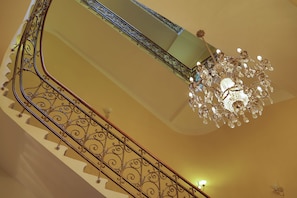 Un escalier orné de rampes en métal ouvragé et un lustre décoré de cristaux.