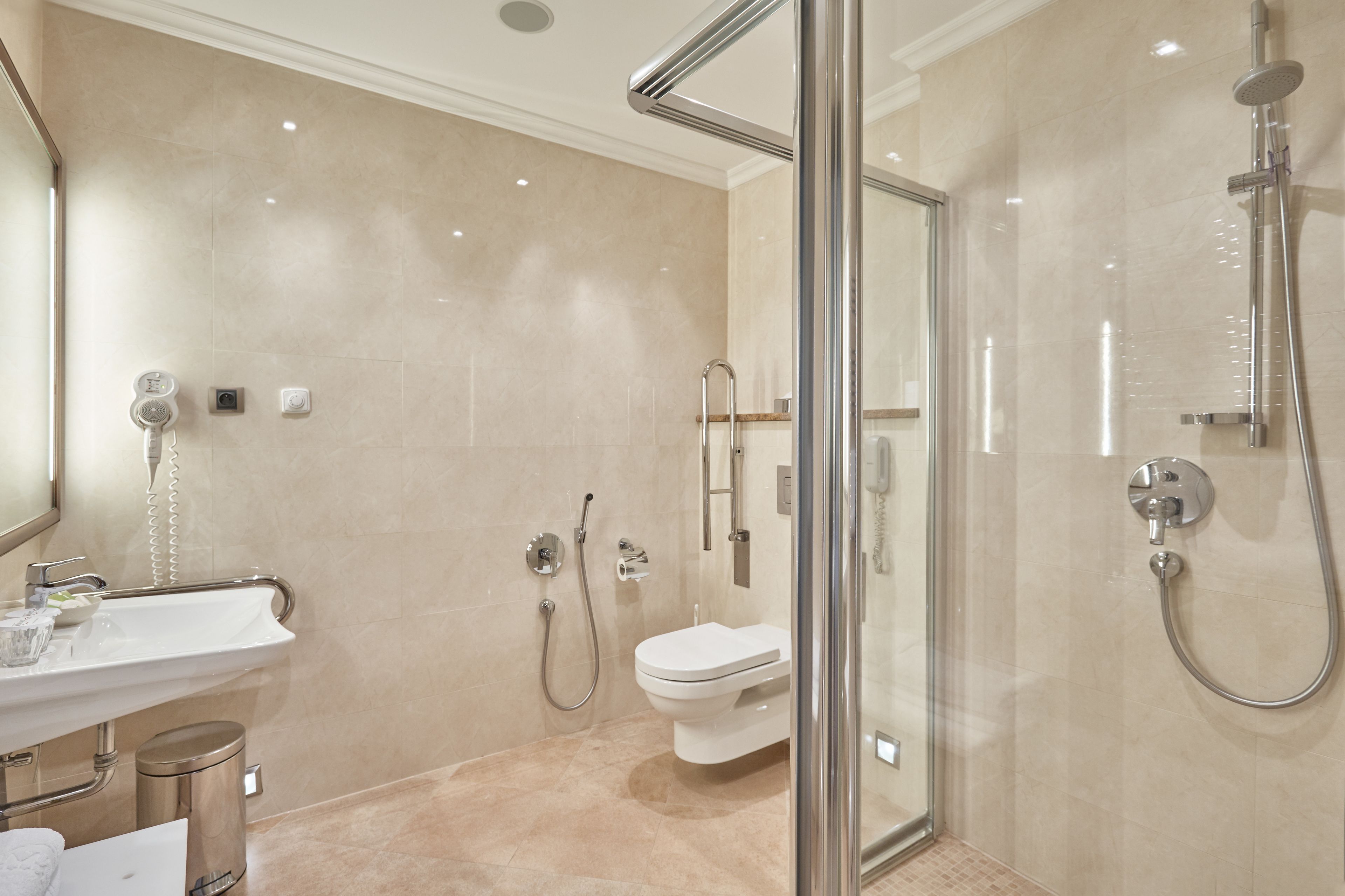 Un baño moderno con ducha de vidrio, un lavamanos blanco y un inodoro.