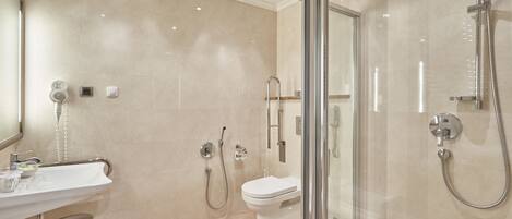 Un baño moderno con ducha de vidrio, un lavamanos blanco y un inodoro.